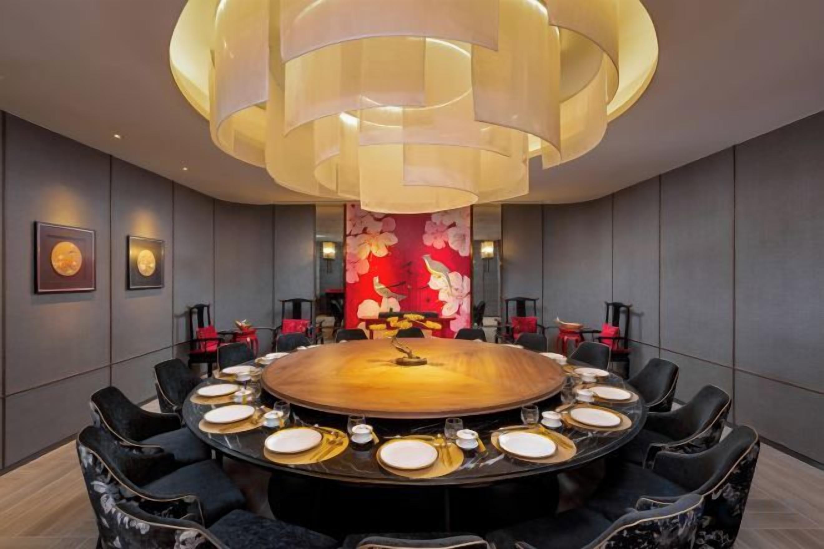 A conference room with a round table, chairs, and a large chandelier.