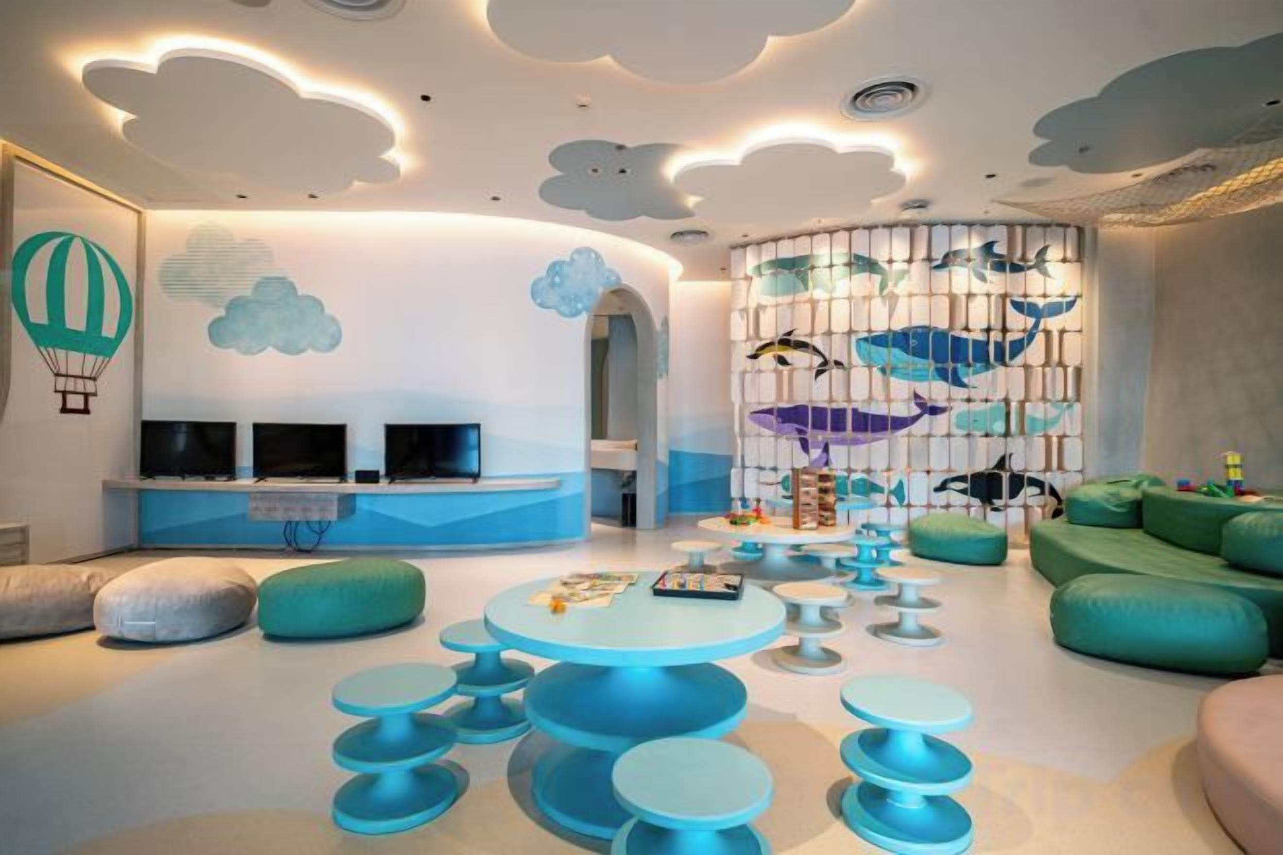 A modern living room with a curved ceiling, a seating area with round tables, and a wall with a fish-themed mural.