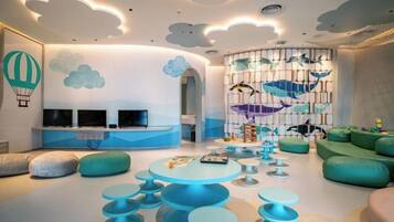 A modern living room with a curved ceiling, a seating area with round tables, and a wall with a fish-themed mural.
