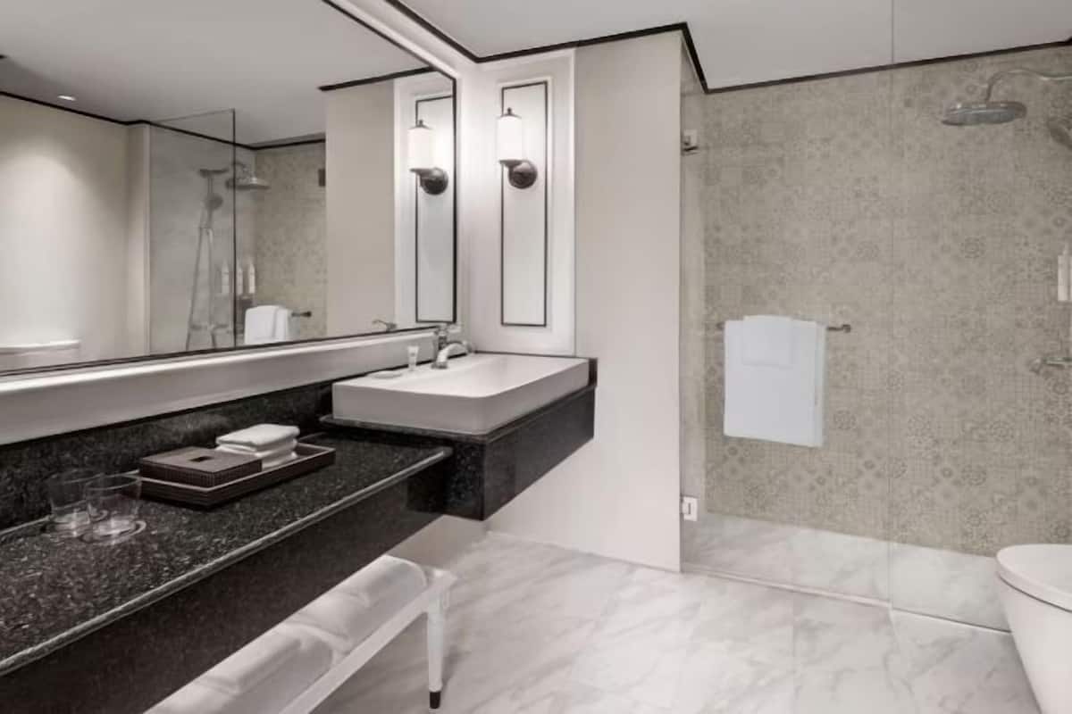 Un bany modern amb un mirall gran, un lavabo, una dutxa i un vàter.