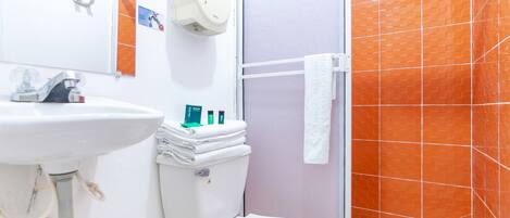 A bathroom with a white sink, toilet, and shower. There is a towel rack with a white towel hanging on it.