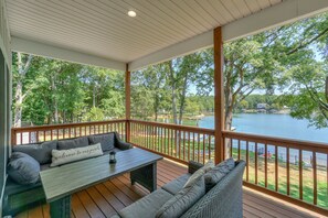 A covered outdoor seating area with a view of a lake and trees. - Lake Norman - Tranquility Cove - Beautiful Lakefront Apartment (Mooresville)
