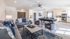 A modern living room with a sofa, coffee table, and chairs, a dining area with a pool table, and a kitchen with white cabinets and a microwave. - Scottsdale's Best: Sun, Swing & Gourmet Eats! (Scottsdale)