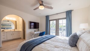 A bedroom with a large bed, a desk, a TV, and a balcony with curtains. - Scottsdale's Best: Sun, Swing & Gourmet Eats! (Scottsdale)