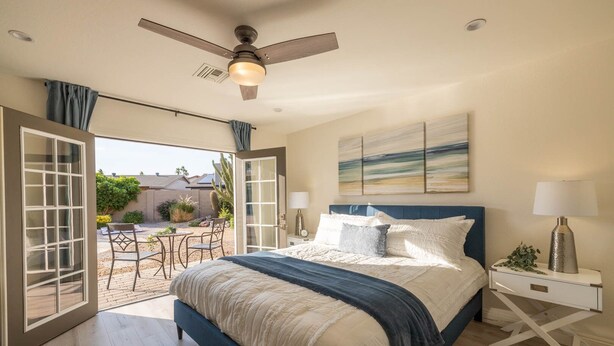 A bedroom with a bed, a nightstand, a ceiling fan, and a view of the outdoors. - Scottsdale's Best: Sun, Swing & Gourmet Eats! (Scottsdale)