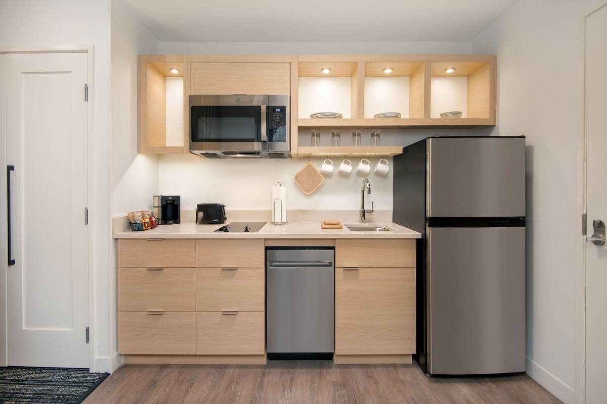 Una cocina compacta con microondas, refrigerador y lavavajillas.