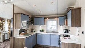 Una cocina compacta con gabinetes azules, un microondas integrado y un lavamanos.