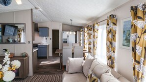 Una sala de estar moderna y luminosa, con sofá, comedor y cocina.