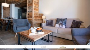 A modern living room with a wooden ceiling, a sofa with decorative pillows, a dining area with chairs, and a wooden coffee table with a basket of bread.