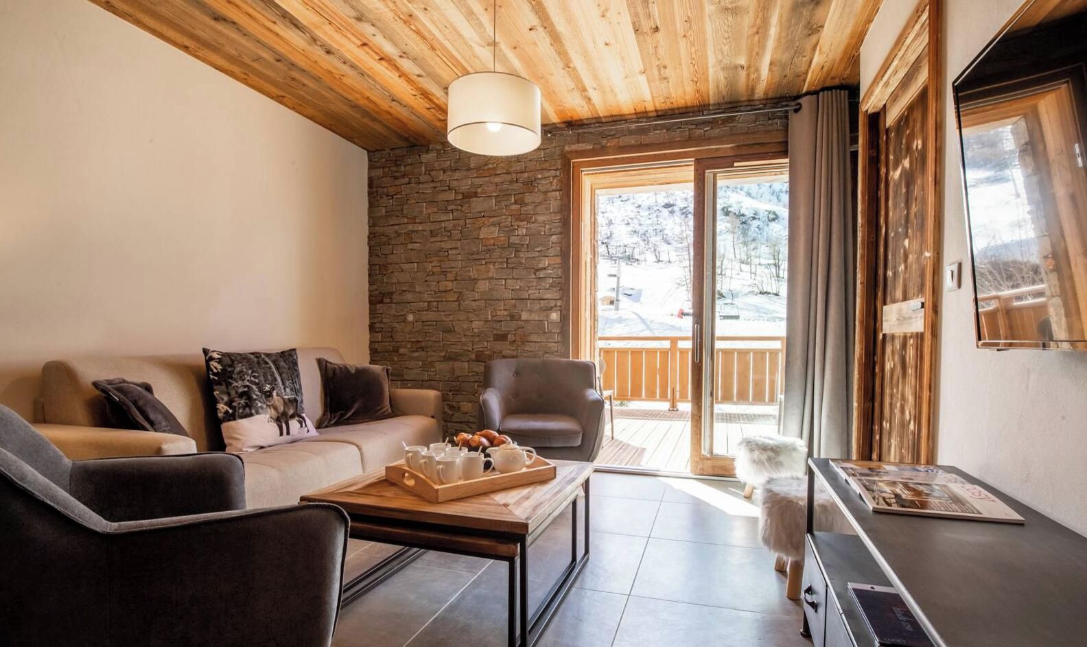 Un salon chaleureux avec un mur en pierre, un plafond en bois, un canapé, une table basse et un chien.