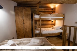 Ein Schlafraum mit Etagenbetten, Holzwänden und einem Kleiderschrank.