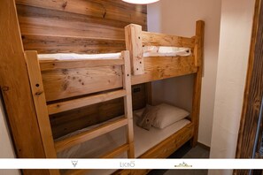 Una cama litera de madera con una escalera, un almohadón y una pared con diseño de paneles de madera.