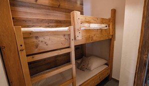 Una cama litera de madera con una escalera, un almohadón y una pared con diseño de paneles de madera.