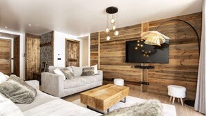 A modern living room with a sofa, coffee table, and a TV mounted on a wooden wall. - Marmotte 103 - New apartment up to 10 guests with stunning view (BONNEVAL SUR ARC)