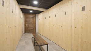 Un couloir avec des casiers en bois, des panneaux numérotés et un banc.