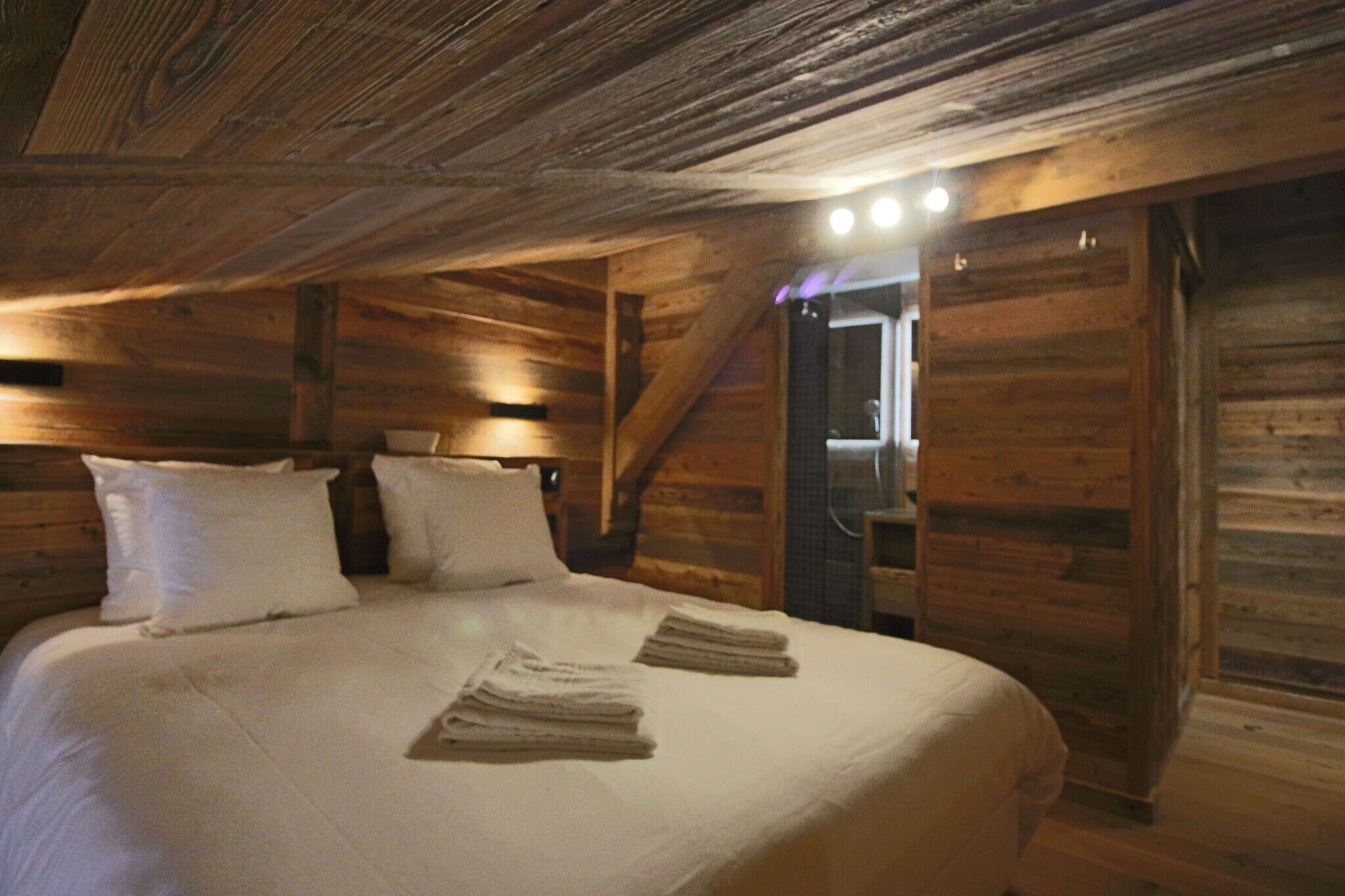 Une chambre dans une cabane en bois, avec un lit, des oreillers et une table de chevet.
