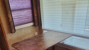 Een houten eettafel met banken, een raam met luiken en een houten vloer.