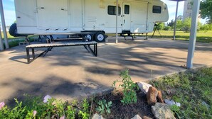 Een overdekte parkeerplaats met een witte camper onder een metalen dak.