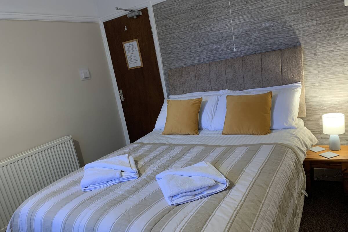 A neatly made bed with striped bedding and two folded towels.