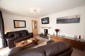 A living room with a sofa, coffee table, fireplace, TV, and artwork.