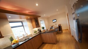 A modern kitchen with wooden cabinets, a stainless steel sink, and a built-in island. - Abhainn Cottage (Isle of Lewis)