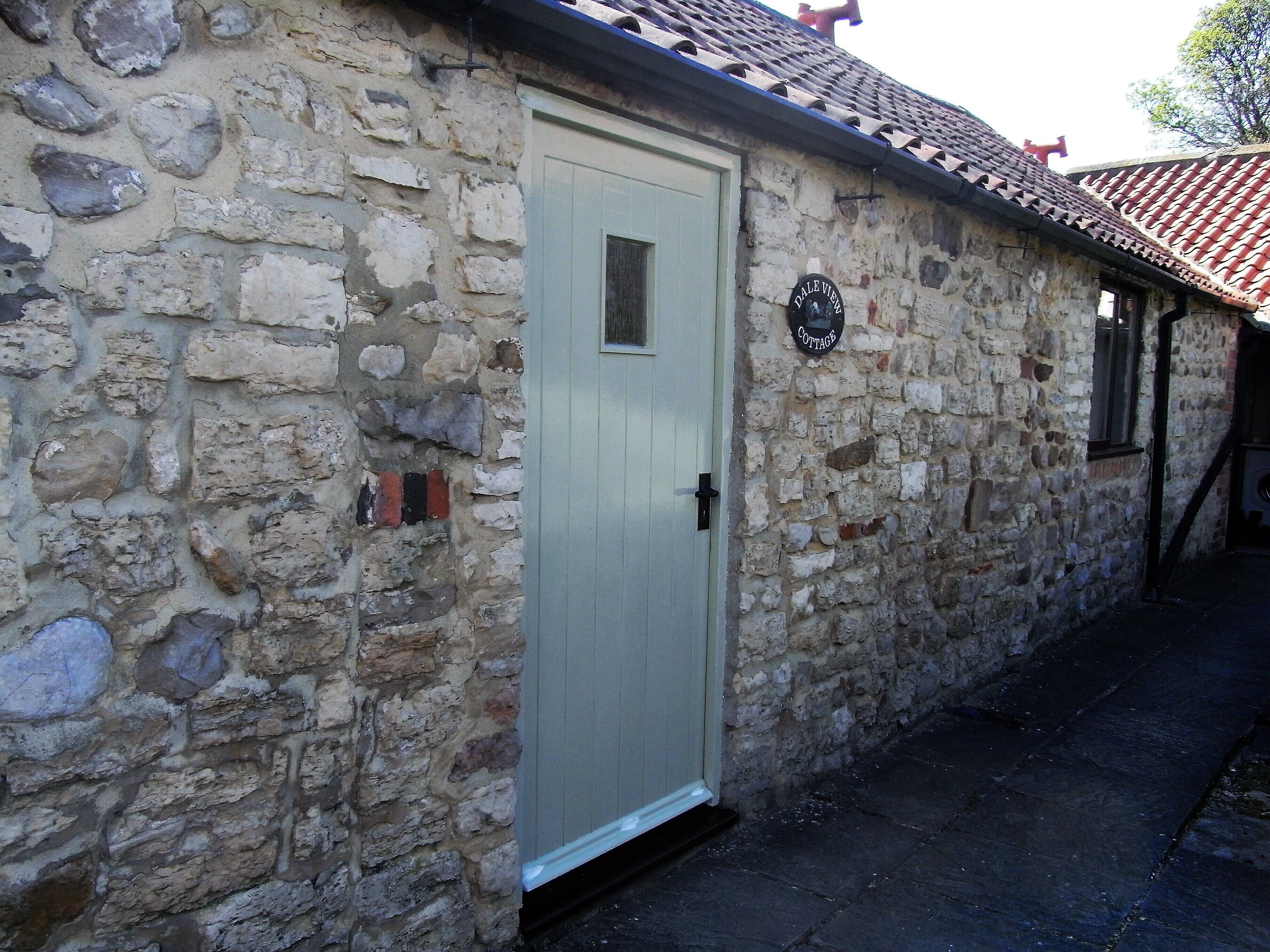 A stone cottage with a white door, a small window, and a sign reading "Dale View Cottage."