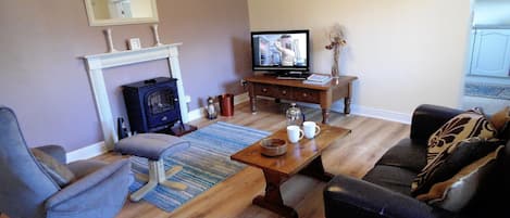 A living room with a fireplace, a television, a sofa, and a coffee table.