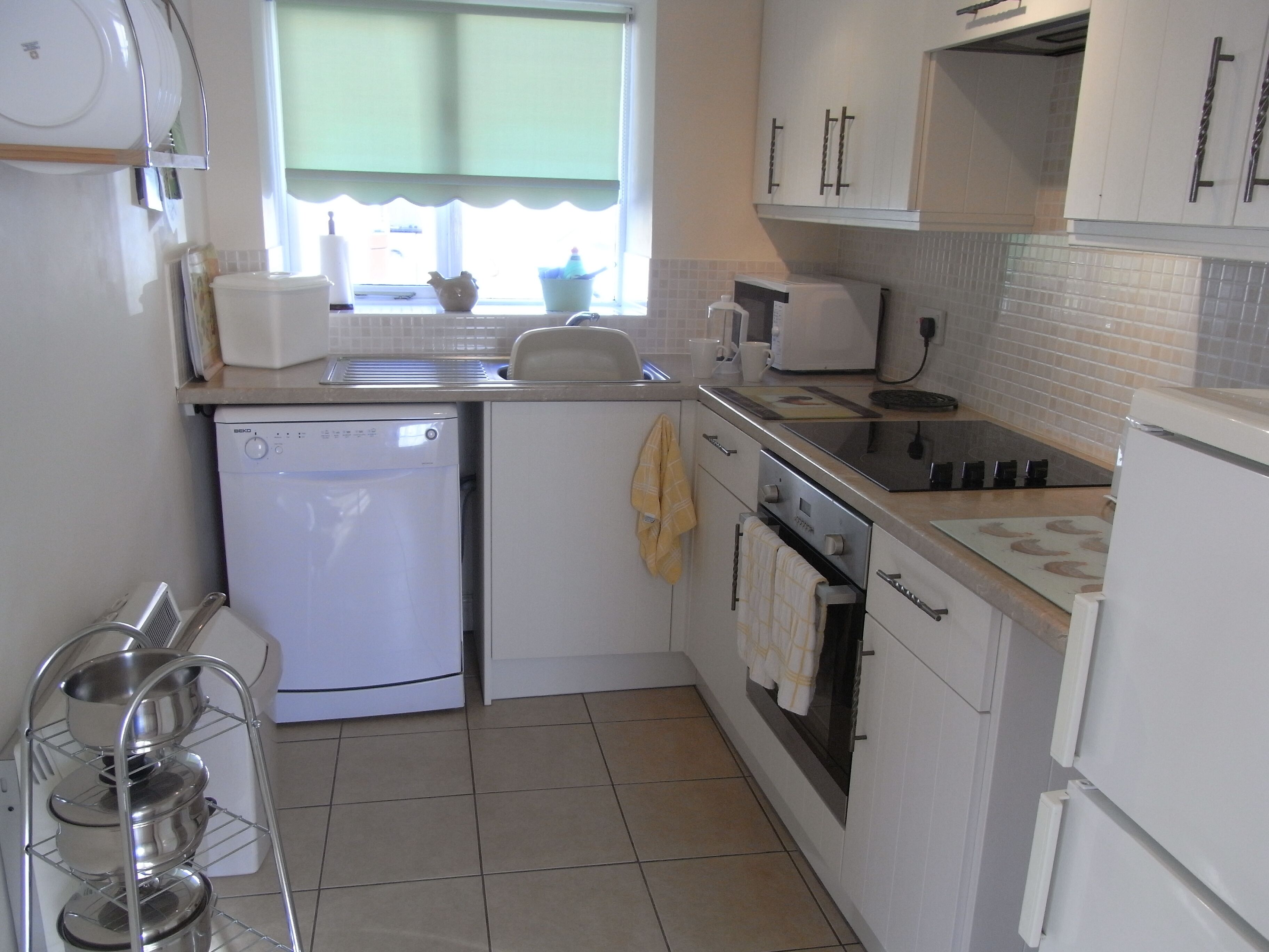 A compact kitchen with a dishwasher, stove, and sink.