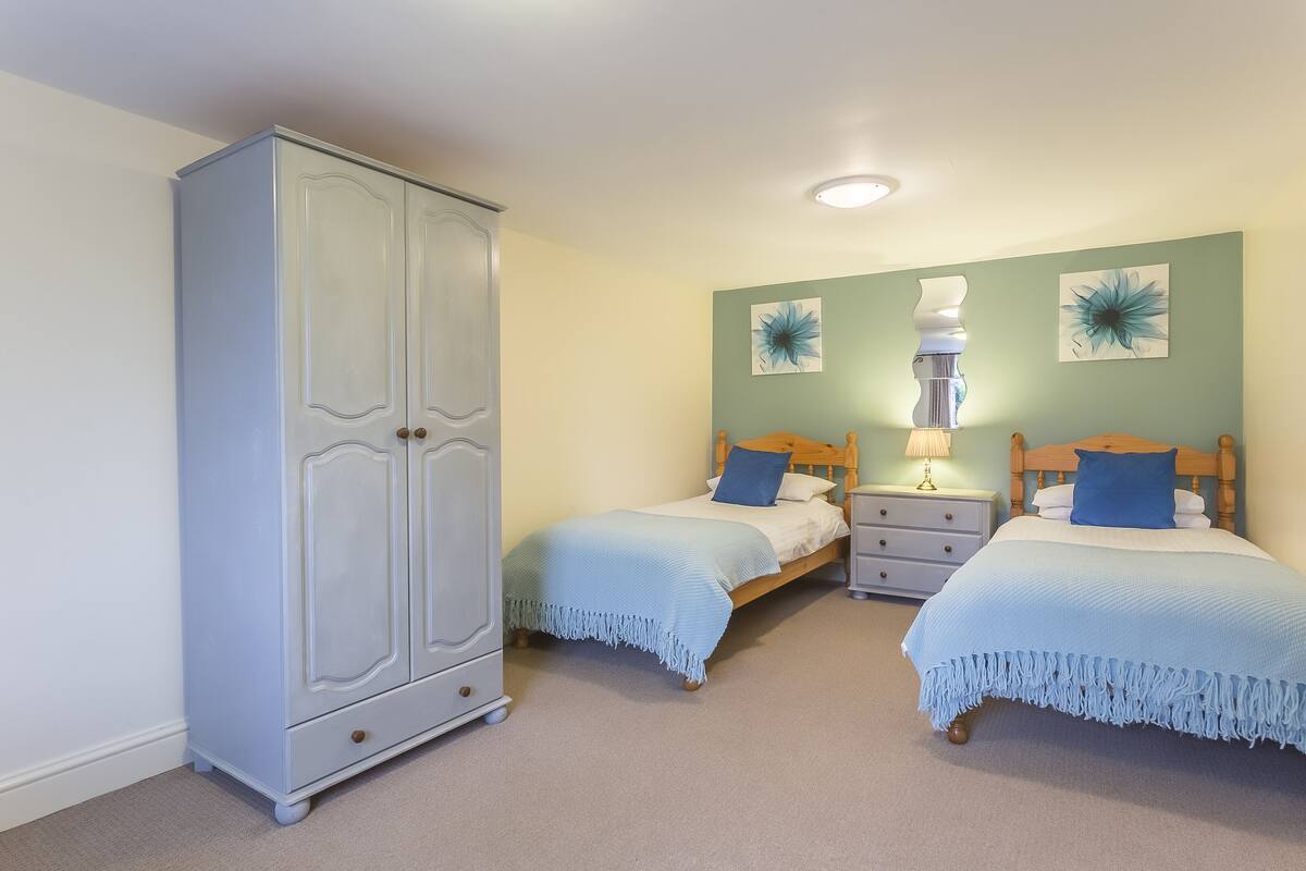 A bedroom with two beds, a wardrobe, and decorative wall art.