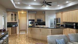 A modern kitchen with wooden cabinets, a central island, and a ceiling fan. - Relaxing and Inviting Home, 2 Prime Suites, seasonally heated pool on 2.5 acre.  (Atascadero)