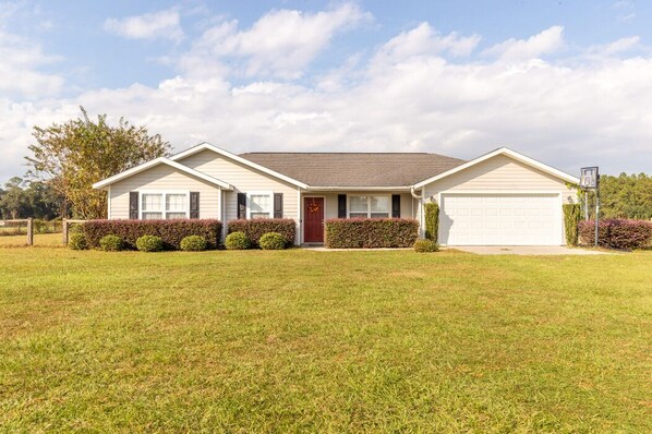 A two-story house with a garage, a front door, and a well-maintained lawn. - 6+ Sleeper Farm Escape with HUGE Yard and RV Hookup is Out Standing in its Field (Lake Butler)