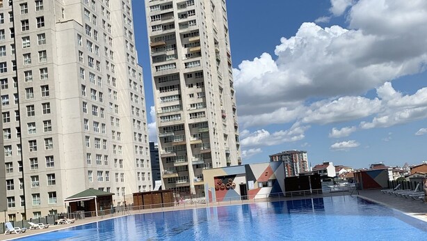 Una piscina con sillas de descanso y un complejo de edificios al fondo.
