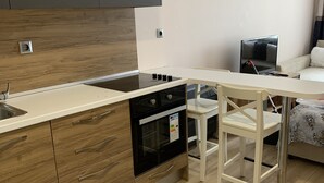 Una cocina moderna con estufa integrada, armarios de madera y encimera blanca.