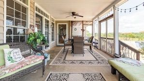 Eine überdachte Veranda mit Korbmöbeln, einem Deckenventilator und Blick auf die Landschaft.