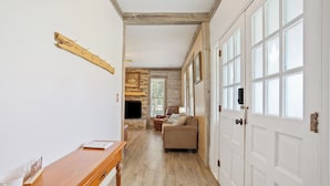 A hallway with a wooden bench, a sofa, and a television in the background. - Villa 30 mins to Waco - Private Pool, Hot Tub, Gym and Fire Ring (Gatesville)