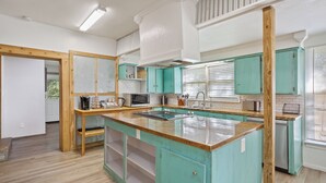 A kitchen with teal cabinets, a wooden island, and white appliances. - Villa 30 mins to Waco - Private Pool, Hot Tub, Gym and Fire Ring (Gatesville)