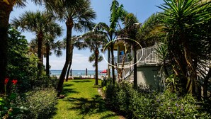 A garden pathway leading to a building with a balcony overlooking a beach. - Cozy 1BR Condo w/ 0 min walk to beach! Spectacular views! Summer 2026 open! (North Redington Beach)