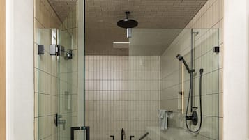 A modern bathroom with a glass-enclosed shower, a large bathtub, and a white vanity with a towel rack.