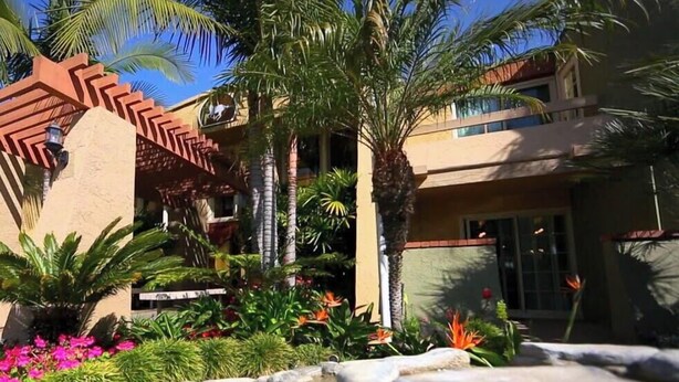 A hotel exterior with a landscaped garden, palm trees, and a pool area. - Enjoy beautiful beaches of Del Mar, minutes to San Diego. Walk to restaurants.  (Solana Beach)