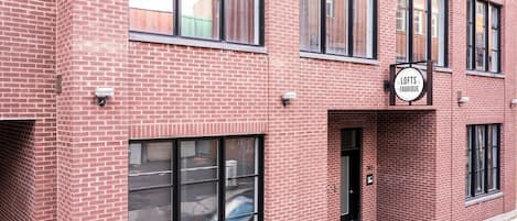 A red brick building with large windows and a sign that reads 'Lofts de la Fabrique.'