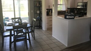 Una cocina equipada con microondas, horno y refrigerador. Cuenta con un comedor con mesa y sillas.