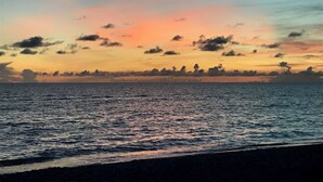 Un atardecer sobre un mar tranquilo con una costa lejana.