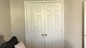 A room with a bed, a ceiling fan, and a white door. - Simple Serenity  (Fredericksburg)