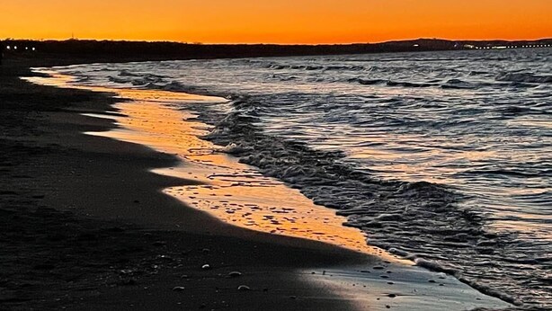 Una playa al atardecer con olas lamiendo suavemente la orilla.