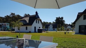 Un patio con mesa y sillas de vidrio, una taza de café y un paraguas grande.