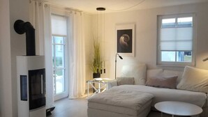 Una sala de estar moderna con un sofá, una mesita redonda, una chimenea y una ventana con cortinas.
