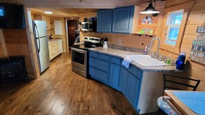 Une cuisine compacte avec des meubles de rangement en bois, un four encastré, un four à micro-ondes et un évier.
