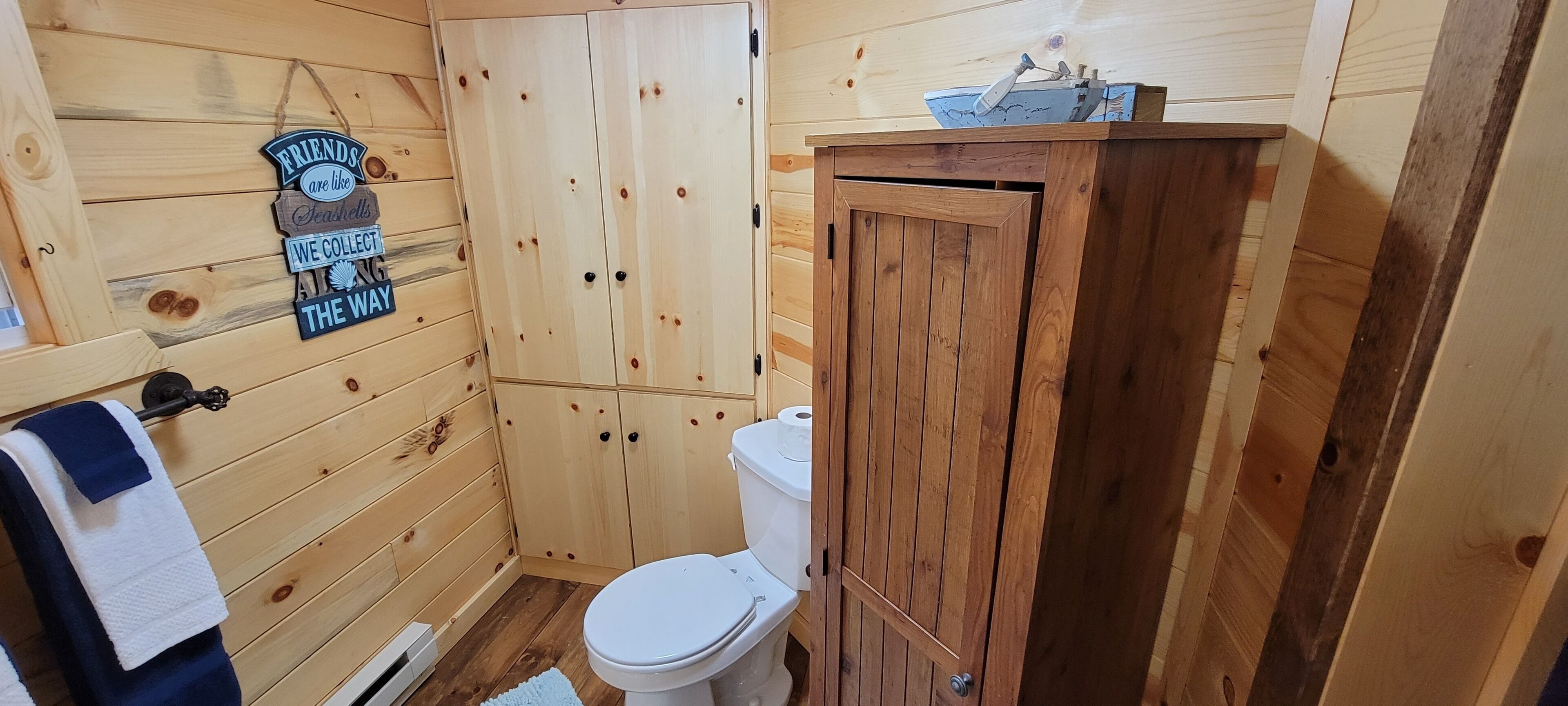 Une salle de bain en bois comprenant des toilettes, un meuble en bois et un porte-serviettes avec une pancarte.