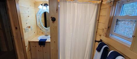 A wooden cabin bathroom with a sink, mirror, and window.