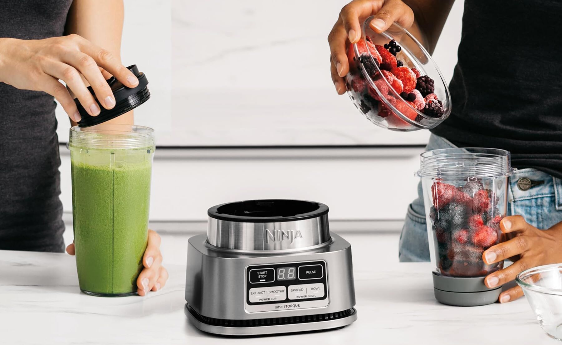 Una cocina con una licuadora y una persona preparando un batido verde.